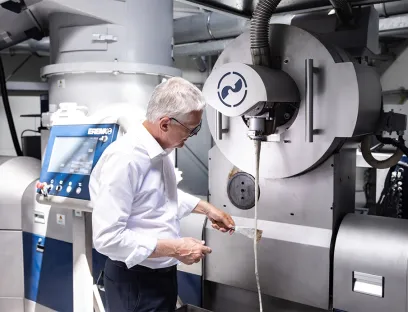 Manfred Hackl, CEO of the Erema Group, inspects the melt filter discharge of an Intarema system. With high-performance recycling technology and ongoing research and development, the company considers itself well-equipped for the next phase of growth in plastics recycling